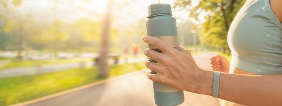 Person hält Trinkflasche beim Sport – Wasser trinken für Herz und Kreislauf